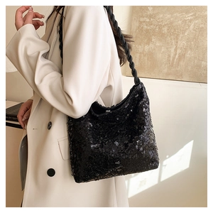 Detail of black sequined handbag with woven leather shoulder strap on a model