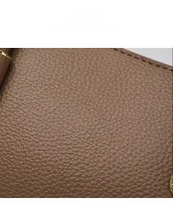 Close-up of brown lychee grain leather texture with precise stitching and gold hardware