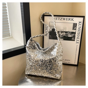 Detail of silver sequin handbag featuring a textured braided handle and modern sparkle