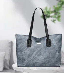 Close-up of a grey tote bag with stone texture on a white marble table in a cozy room