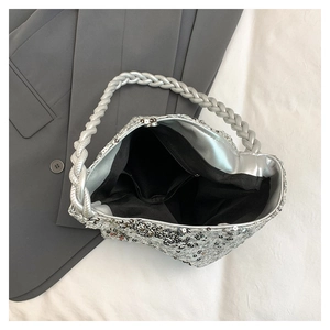 Detail of silver sequin handbag showing woven handle and interior storage with zipper pocket