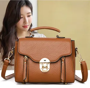 Close-up of brown litchi pattern leather bag with golden metal lock and side zippers