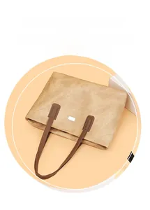 Detail of khaki tote bag showing crinkled texture and silver square metal plaque
