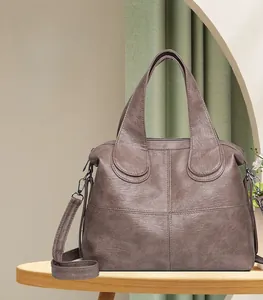 Detail of a large capacity dark brown retro leather handbag with cross stitching and strap