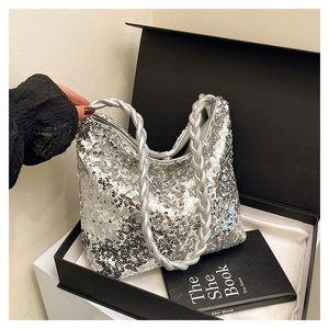 Detailed view of silver sequin tote bag with braided handle in a black gift box