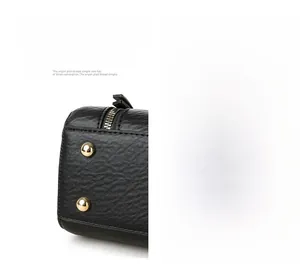 Close-up of black litchi grain leather bag base with golden protective metal rivets
