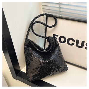Close-up of black sequin handbag featuring a unique twisted woven handle and magnetic closure