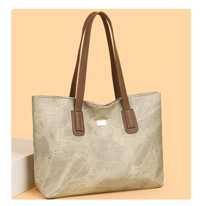 Detail of large tote bag showing marbled texture material and silver metal logo plaque