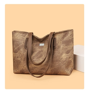 Detailed macro view of retro brown stone pattern tote bag with metal emblem and leather strap