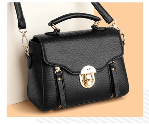 Detail of black lychee texture leather with elegant gold metal lock on square bag