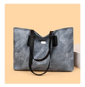 Detail of grey marble textured tote bag with black handles and metal plate ornament