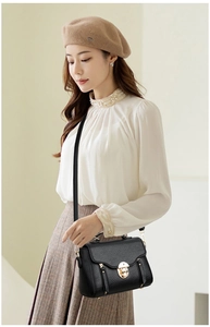 Close-up of black lychee grain leather crossbody bag with elegant gold lock and side zipper