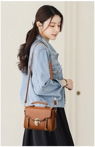 Close-up of brown crossbody bag with scalloped flap and gold hardware on model
