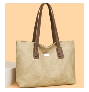 Close-up of textured tote bag showing unique pleated material and silver metal plaque