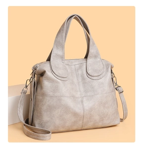 Detail of beige faux leather handbag featuring litchi grain texture and cross-stitch pattern