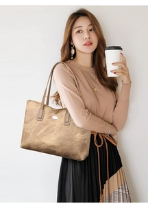 Detail of vintage brown tote bag featuring marble texture and metallic logo on model