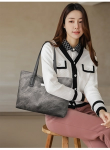 Close-up of a large grey tote bag with marble texture worn by an elegant model