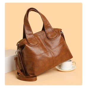 Detailed view of brown lychee grain leather handbag with vintage stitching and twin handles