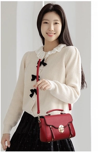 Close-up of red lychee pattern PU leather crossbody bag with golden buckle detail