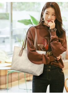 Detailed view of a cream leather tote bag carried by a model in a cafe setting