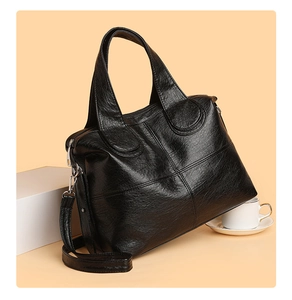 Detail of black textured leather handbag with vintage cross-stitching and silver hardware