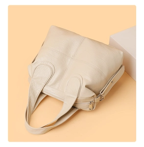 Detail view of beige faux leather tote showing cross stitching and metallic zipper