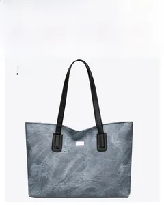 Detail of blue tote bag showing marble texture, black leather strap and silver logo