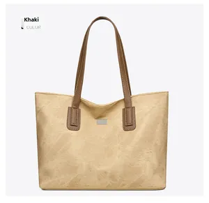 Detail of khaki tote bag showing vintage texture, brown straps, and metal buckle