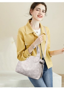 Detail of light gray textured leather tote bag with silver hardware on a model