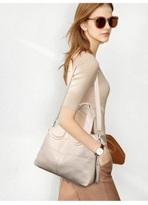 Detail of light beige litchi texture leather bag with silver metal buckles and shoulder strap