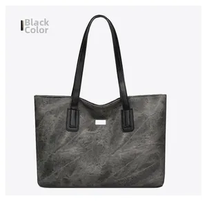 Detail of a large black tote bag featuring textured faux leather and a metal logo plaque