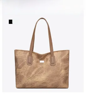 Front detail of vintage brown tote bag with textured finish and white square metal plate
