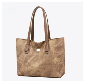 Detail view of large brown tote bag with vintage texture and minimalist metal plate