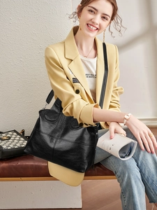 Close-up of black textured leather handbag with stitching details and adjustable strap