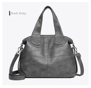 Detail of dark grey leather handbag showing double handles and sturdy stitching
