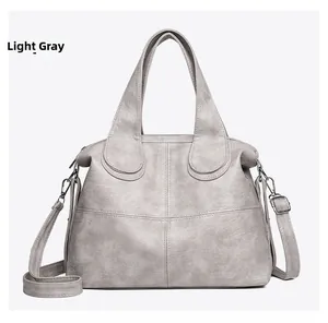 Detailed view of light grey synthetic leather bag with stitching and shoulder strap