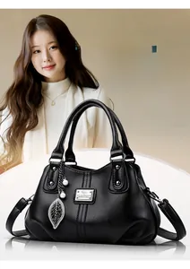 Detail of black pebbled leather tote bag with elegant leaf pendant and dual handles