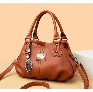 Detail of brown litchi pattern leather handbag with pearl leaf pendant and dual handles