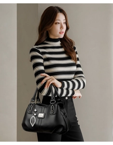 Detail of black pebbled leather handbag featuring pearl and metallic leaf charm