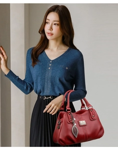 Close-up of red pebbled leather handbag with leaf charm and elegant pearl detail