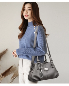 Detail of dark gray lychee pattern leather tote with silver leaf pendant and strap