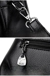 Macro detail of black litchi grain leather texture with silver metal zipper and clasp