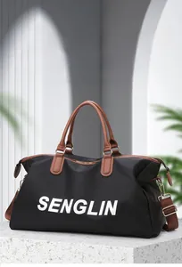 Detail of black travel bag with brown leather handles and adjustable shoulder strap