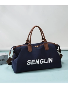 Detail of navy nylon travel bag with brown leather handles and SENGLIN logo