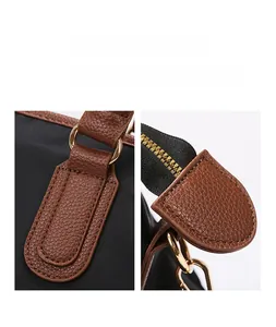 Detail of reinforced stitching on black nylon and brown leather with golden D-ring hardware