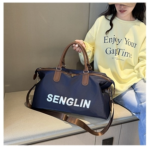 Detail of navy nylon travel bag with brown leather handles and SENGLIN logo