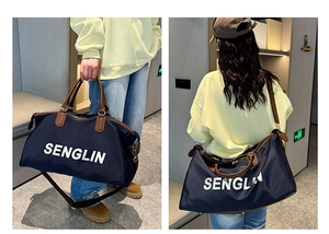 Detail of navy canvas travel bag with brown leather handles and adjustable shoulder strap