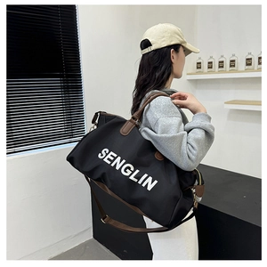 Detail of a black large capacity travel bag with leather handles and white text