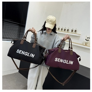 Detail of black and burgundy large travel bags with durable handles and logo