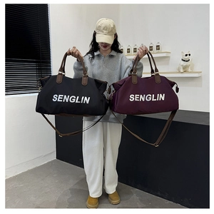 Detail view of large nylon travel bags in black and burgundy with leather handles